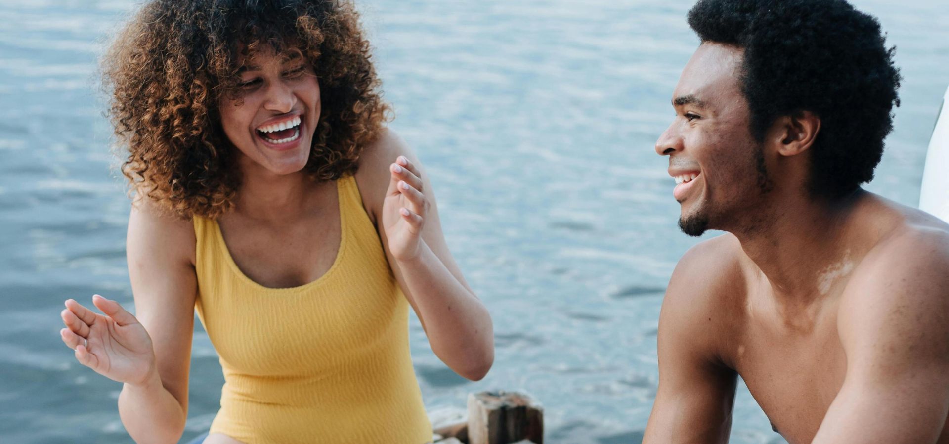 A cheerful moment by the lake featuring a couple enjoying a picnic, laughter, and sunny weather.