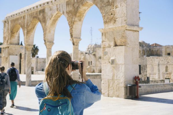 A tourist photographs the ancient stone arches in Jerusalem's Old Town, capturing the essence of travel and history.