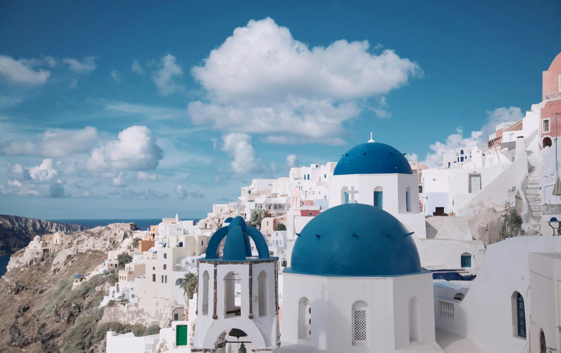 Breathtaking view of Oia's iconic blue-domed churches against a vibrant sky in Santorini, Greece.