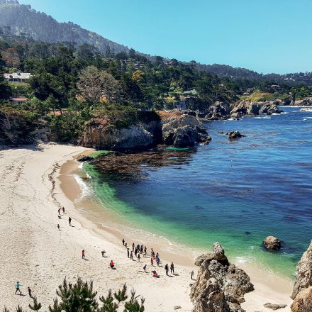 A picturesque view of the coastline with people enjoying the beach at Carmel-by-the-Sea, California.