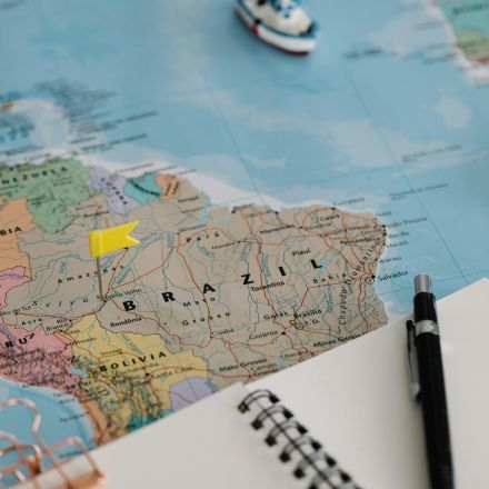 Close-up of Brazil on a world map with a notebook and pen for trip planning.