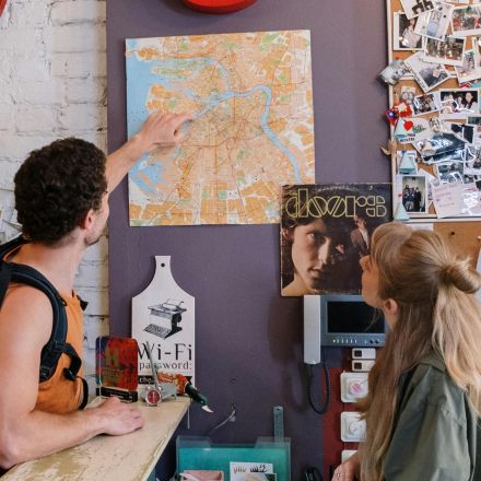 Backpackers consulting map at hostel reception desk for directions.